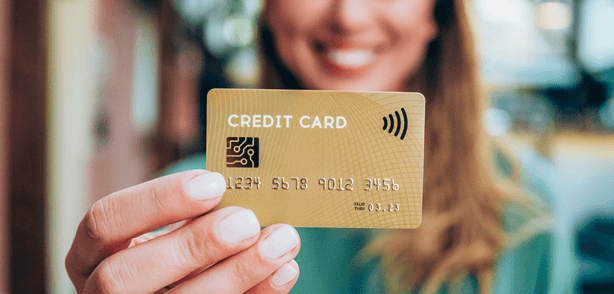 Business Credit Card - Beautiful young female shopper holding a credit card - focus on foreground.